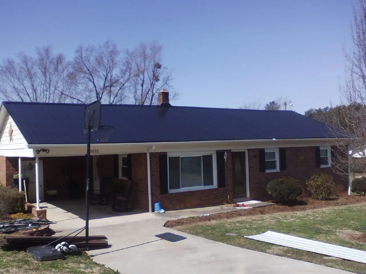 Finished dark blue metal roof on a brick ranch with a carport in Beaverdam