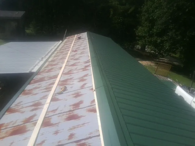 Old rusted panels beside newly installed green metal roofing — Wind Damage Roof Repair by Roofing Brothers in Beaverdam