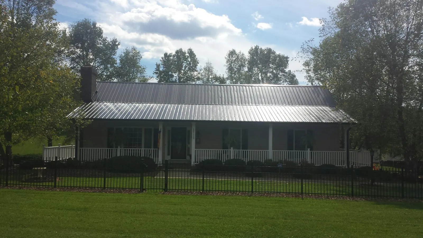 Gray metal roof on a brick ranch with a full width front porch — Gutter Guard Installation work by our crew in Beaverdam