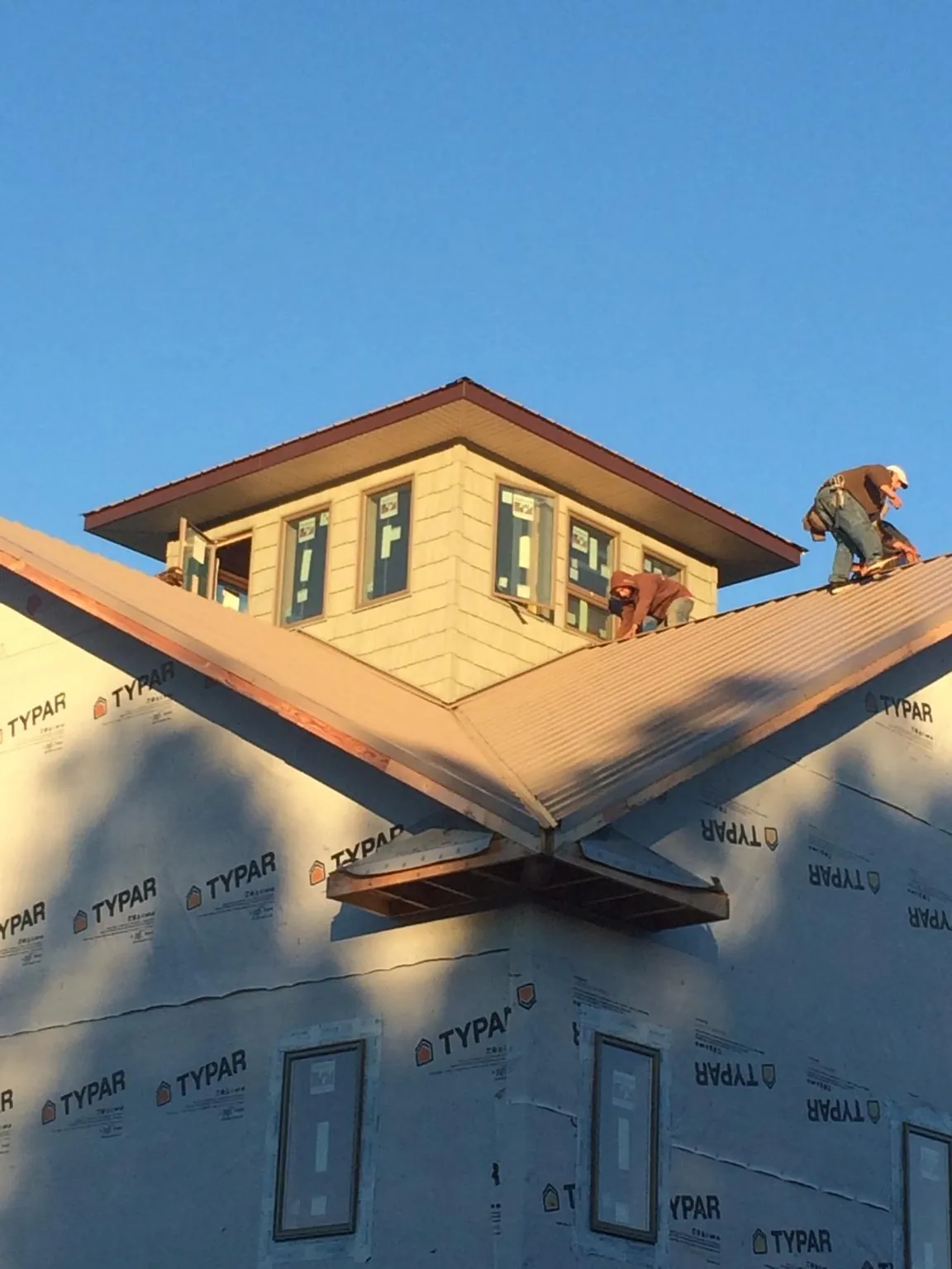 Roofers working around a rooftop cupola on a new metal roof at sunset — Roof Waterproofing in Beaverdam by Roofing Brothers